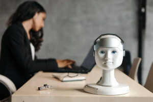 AI in Business can be challenging, AI is on a desk in the office with a woman in Background. The Picture should be a symbol of AI in Business